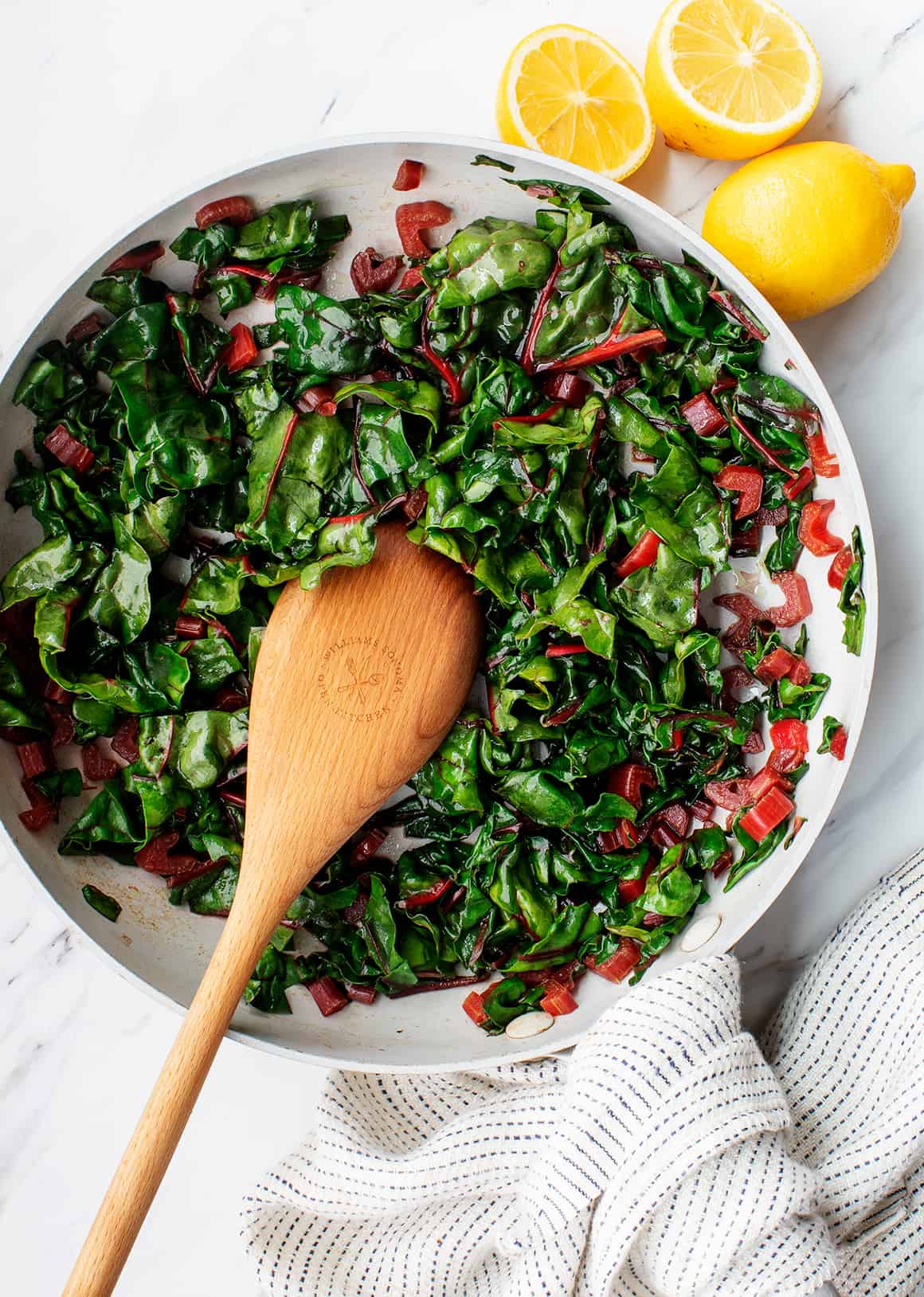 Sautéed Swiss chard in skillet with wooden spoon